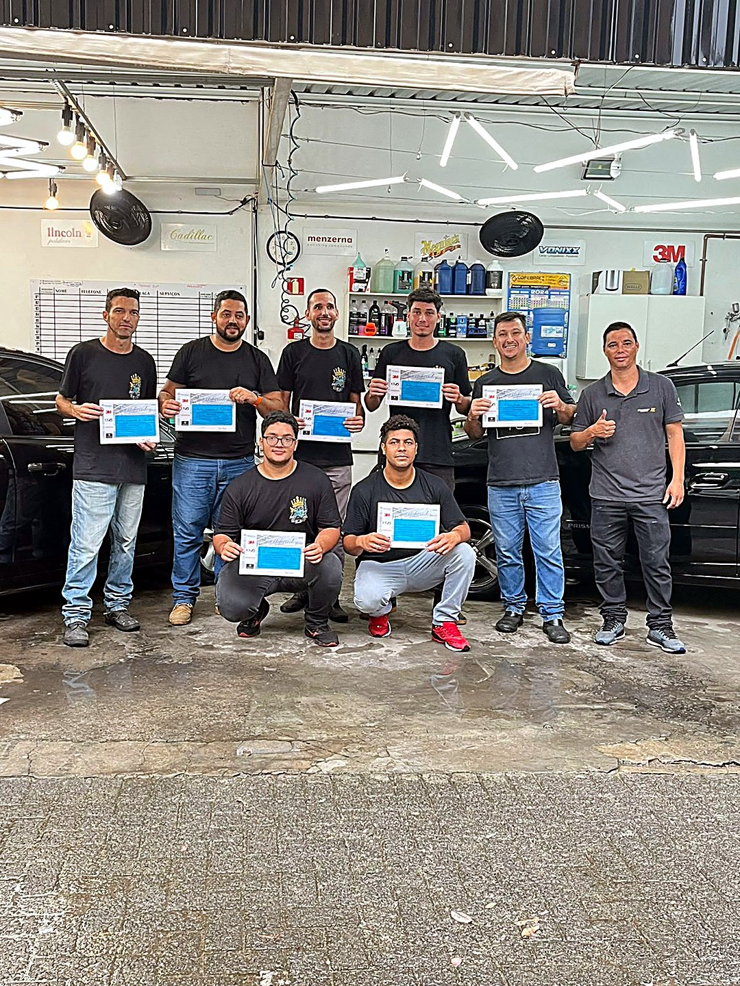 Turma do curso de estética automotiva de 13/04/2024 segurando os certificados na oficina Wash