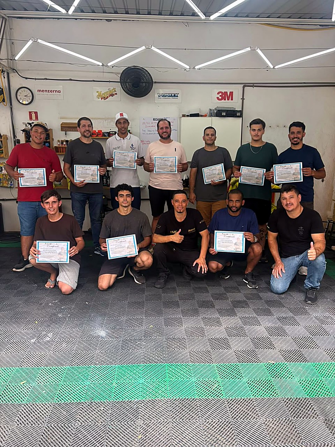Turma do curso de estética automotiva segurando os certificados na oficina Wash